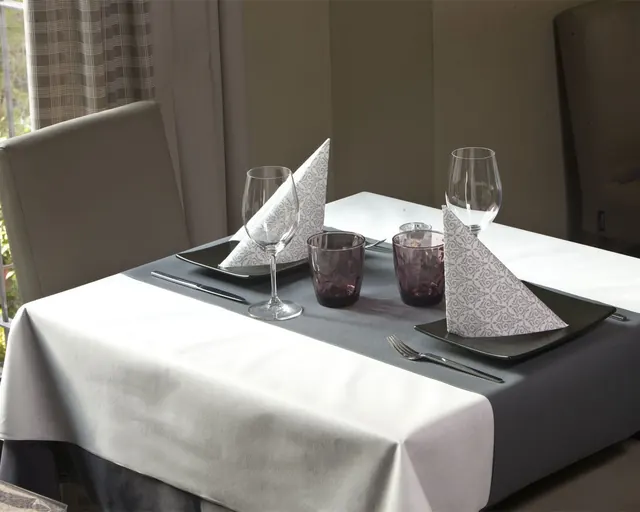 Mantel blanco con camino gris y servilletas plegadas